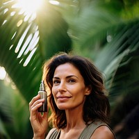 close up face shot photo of a middle aged hispanic woman face holding serum bottle close to her face.  