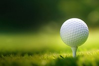 photo of a close up the golf ball on tee pegs ready to play, light green, natural light. 