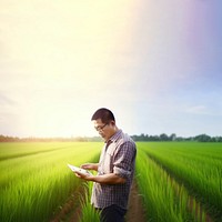 photo of a man farmer with tablet working in rice field.  