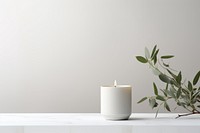 Candle on a white table with vases plant candlestick windowsill.