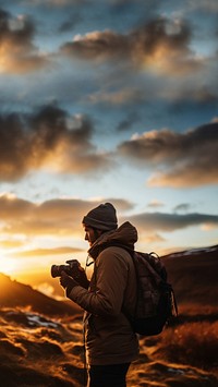 front-left view Photo of a man holding camera, taking picture in the wild in a chilly day. 