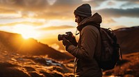 front-left view Photo of a man holding camera, taking picture in the wild in a chilly day. 