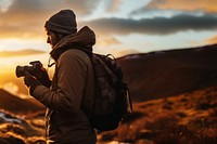 front-left view Photo of a man holding camera, taking picture in the wild in a chilly day. 