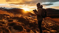 front-left view Photo of a man holding camera, taking picture in the wild in a chilly day. 