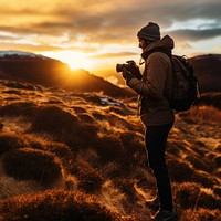 front-left view Photo of a man holding camera, taking picture in the wild in a chilly day. 