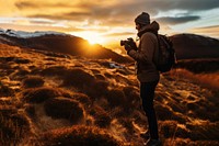 front-left view Photo of a man holding camera, taking picture in the wild in a chilly day. 