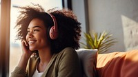 photo of A black woman sitting on a couch happy with wearing headphones in a minimal living room. 