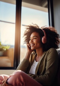 photo of A black woman sitting on a couch happy with wearing headphones in a minimal living room. 