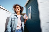 Portrait photo of a happy woman holding aluminum can looking at out side on minimal home. 