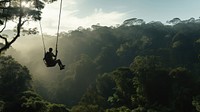 Photo of a man playing zipline through jungle. 