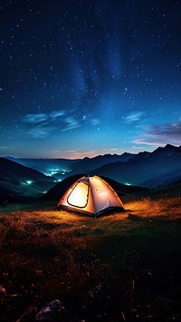 Photo of a tent, in a grass land, moutain in the background, at night, sky full of stars. 