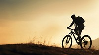 photo side view sillhuette of man riding a bicycle bike uphill with natural light. 