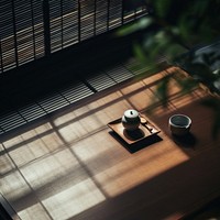 A serene tea setup with a teapot and cup on a wooden table. Sunlight filters through blinds, casting shadows. Peaceful tea scene with calming shadows and light.