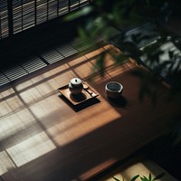 Sunlit wooden table with a teapot and cup, casting soft shadows. Peaceful, serene atmosphere with a focus on tea, shadows, and natural light.