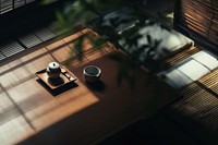 A serene tea set on a wooden table with soft lighting and shadows. The tea set and table create a calming, peaceful atmosphere with natural light and shadows.