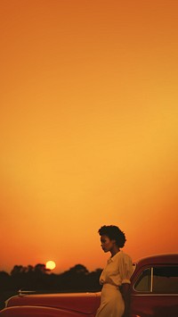 Woman standing by her car, sunset. 