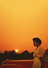 Woman standing by her car, sunset. 