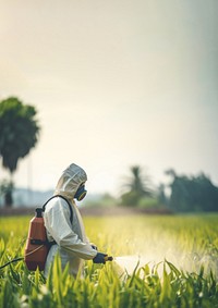 Asian farmer wear safety clothes with protective mask spraying organic pesticides. 