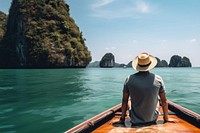 Back view photo of a man sitting in front of a boat, in Krabi in sunny day. 