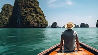 Back view photo of a man sitting in front of a boat, in Krabi in sunny day. 