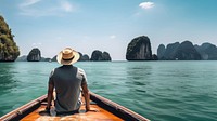 Back view photo of a man sitting in front of a boat, in Krabi in sunny day. 