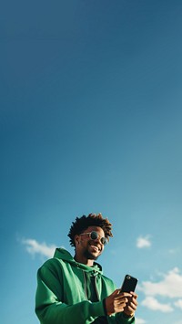 photo of black man wearing green tone outfit using smartphone. 