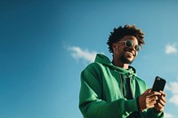 photo of black man wearing green tone outfit using smartphone. 