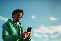 photo of black man wearing green tone outfit using smartphone. 