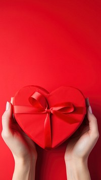 A photo of hands of woman holding a nice shape valentines present on red background. AI generated Image by rawpixel. 