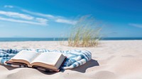 Book on the picnic blanket in beach white sand.  