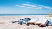 Book on the picnic blanket in beach white sand. 