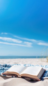 Book on the picnic blanket in beach white sand. 