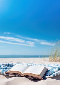 Book on the picnic blanket in beach white sand.  