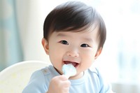 Baby eating spoon toothbrush innocence. AI generated Image by rawpixel.