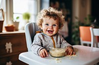 Baby wearing knitted sweater furniture sitting eating. 