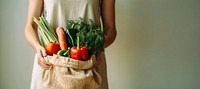 Woman holding vegetable food bag midsection. 