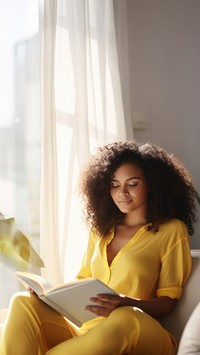 Photo of A relaxed trendy mixed-race african middle aged woman with long wavy hair with book.  