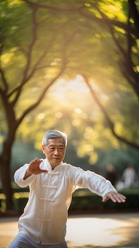 photo of an elderly asian man doing Tai chi in a park.  