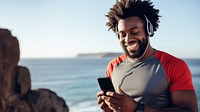 Photo of Portrait of a smiling afro-american sports man stretching his muscular arms before workout by the sea.  