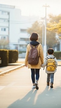 photo of back view asian middle age mom and son walking by holding hand.  