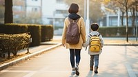 photo of back view asian middle age mom and son walking by holding hand.  