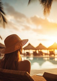 Woman relaxing by the pool in a luxurious beachfront hotel resort at sunset enjoying perfect beach holiday vacation.  