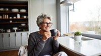 Product photography of a mature woman drinking black coffee while reading newspaper.  