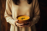 Biege sweater bowl holding pumpkin. 