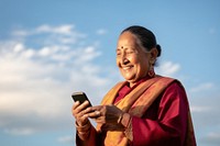 Senior indian business woman using smartphone facetiming adult photo sky. 