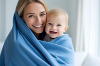 Baby wearing blue towel blanket adult smile. 