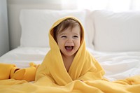 Baby wearing yellow hooded duck towel laughing blanket happy. 