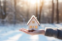 Hand holding small house icon architecture building outdoors. 