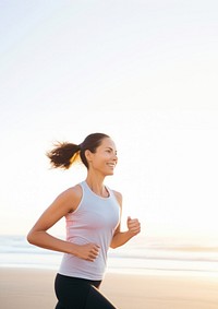 a portrait photo of a happy athletic woman jogging at sunrise by the beach.  