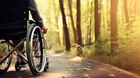 photo Close-up of a person's of Leg disabled hand maneuvering a wheelchair along a forest trail.  